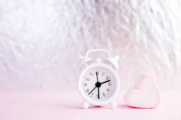 Pastel Valentine achtergrond is gemaakt van marshmallow souffle in de vorm van hartjes op een roze achtergrond en een klok. Valentijnsdag concept met kopieerruimte, tijd om lief te hebben — Stockfoto