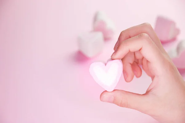 Pastel valentine background made of marshmallows souffle in the form of hearts on a pink background in hands. Valentine's Day concept with copy space — Stock Photo, Image