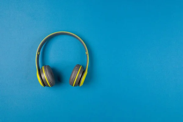 Green wireless headphones on a blue background, selective focus
