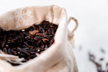 Black wild rice in a bag close-up on a white background, selective focus