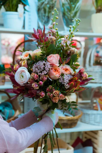 Flower bouquets in hands, backgrounds of bright variety of colors, beautiful details in one bouquet. Selective focus