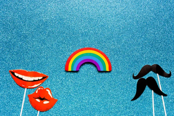 Concetto di relazioni tra uomini e donne dello stesso sesso, flatlay falso photo stand puntelli baffi e labbra arcobaleno su uno spazio di copia sfondo blu lucido — Foto Stock