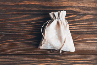 Tahta arka planda beyaz kar taneleri resmi olan tekstil el yapımı bir çanta. Seçici odak.