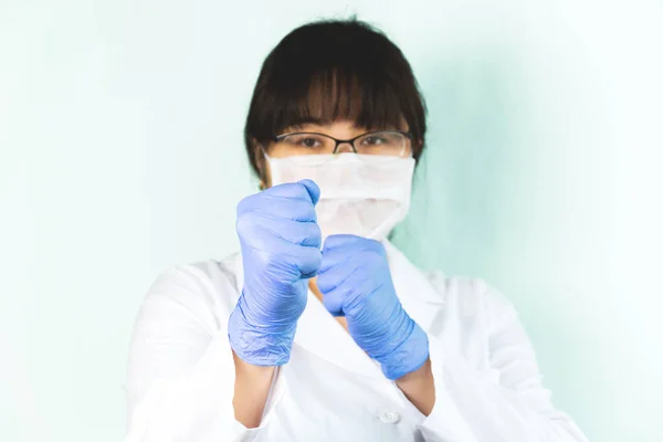 The woman wears a medical mask in a white uniform, protective blue, fighting the virus. Selective focus.