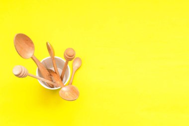 Masa takımı ahşap kaşıklar kağıttan bir fincanda sarı arka plan, üst manzara. Sıfır atık, çevre dostu kavram.