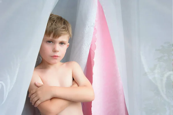 Um rapazinho sem roupa está ao lado da janela. — Fotografia de Stock