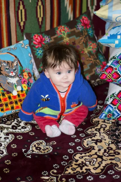 Erstaunliche kleine Mädchen sitzt im Bett auf einem Bett mit bestickten Kissen — Stockfoto