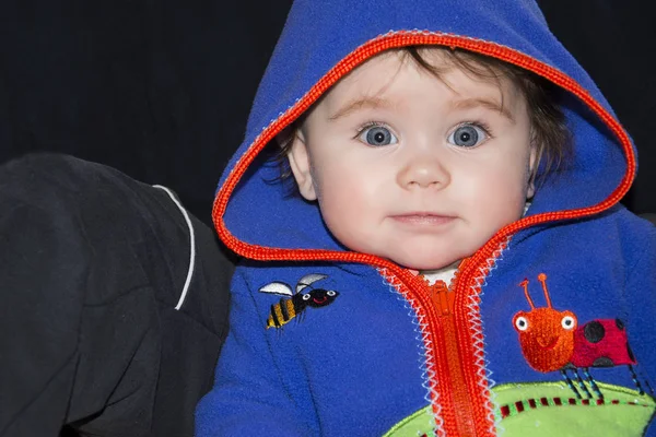 Uma linda menina em um capuz azul sorri encantadoramente para nós — Fotografia de Stock