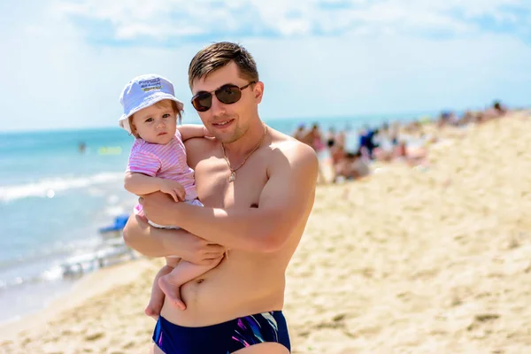 Jovem pai em óculos de sol na praia com uma pequena filha — Fotografia de Stock