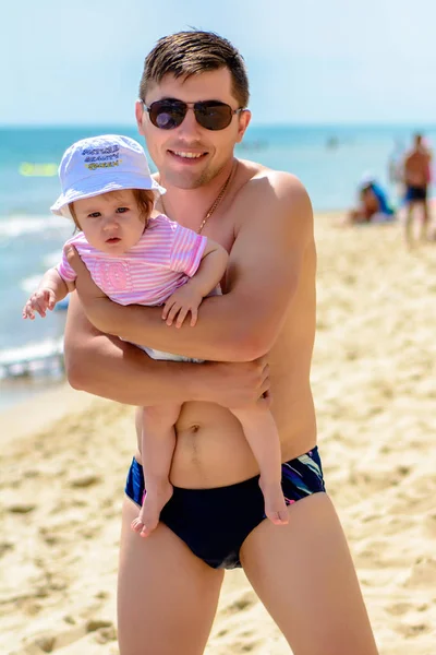 Jovem pai em óculos de sol na praia com uma pequena filha — Fotografia de Stock