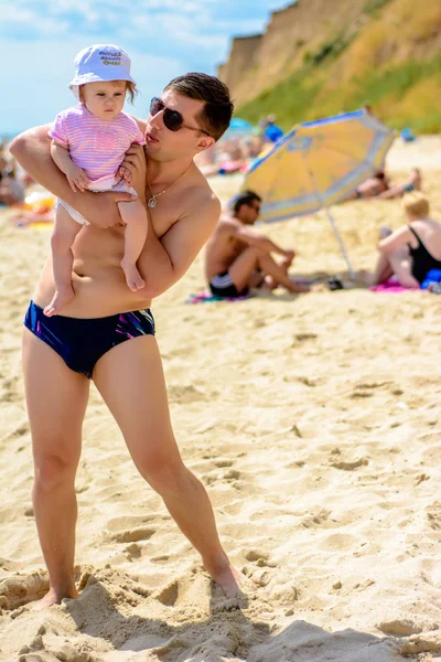 Jovem pai em óculos de sol na praia com uma pequena filha — Fotografia de Stock