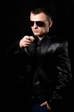 Kameraya bir işaret parmağı bir ceket ve kravat genç bir kaba adam gösterir.