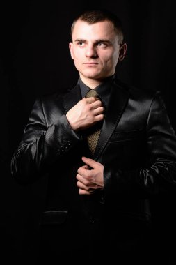 Genç bir işadamı kravat stüdyoda siyah bir zemin üzerine giderir