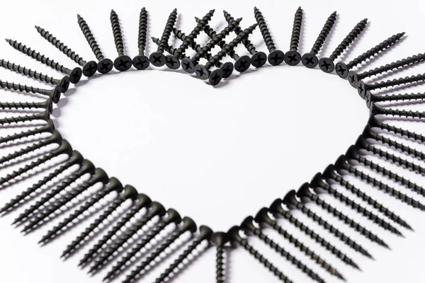 Czarne śruby ułożone w kształcie serca na białym tle — Zdjęcie stockowe