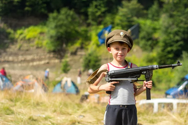 Маленький мальчик в кепке держит трофейное оружие MP-40 времен Второй мировой войны. — стоковое фото