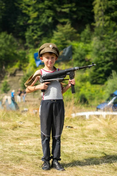 一个小男孩在他的帽子持有一个战利品武器 Mp-40 从第二次世界大战 — 图库照片
