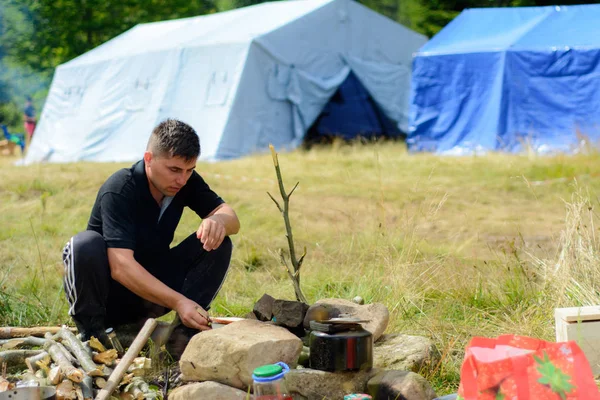 Een man gerechten tijdens het reizen in de natuur op de achtergrond van tenten — Stockfoto