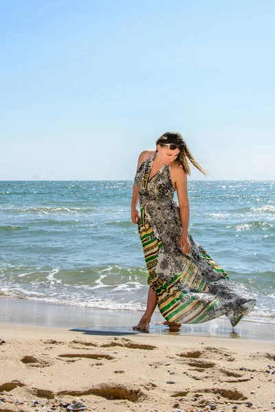 Belle fille debout sur la plage de la mer Noire en lunettes de soleil et robes — Photo
