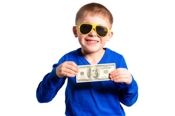 A little boy in a blue sweater smiles and holds a hundred dollars — Stock Photo, Image