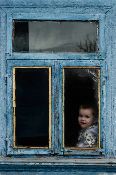 어린 소녀에 페인트는 퇴색 하는 창에 오래 된 오두막에 앉아 — 스톡 사진