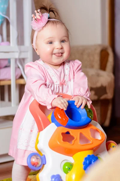 A rózsaszín ruha gyönyörű kislány nevet egy baba ágy — Stock Fotó