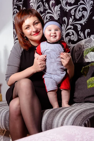 Young mother is glad holding a small child in her arms — Stockfoto