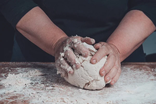 Yaşlı bir kadının büyükanne ekmek yemek pişirmek için bir hamur yoğurma