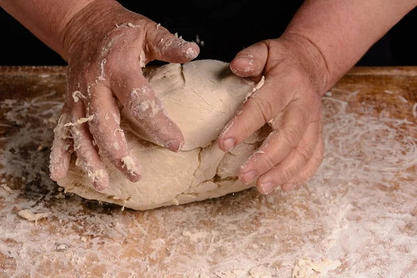 A avó de uma velha está amassando uma massa para cozinhar pão — Fotografia de Stock