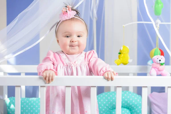 Belo retrato de uma menina em um vestido rosa em um berçário — Fotografia de Stock