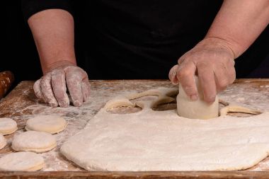 Büyükanne bir hamur dairesel bir bardak masaya sıkar.