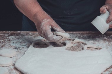 Büyükanne bir hamur dairesel bir bardak masaya sıkar.