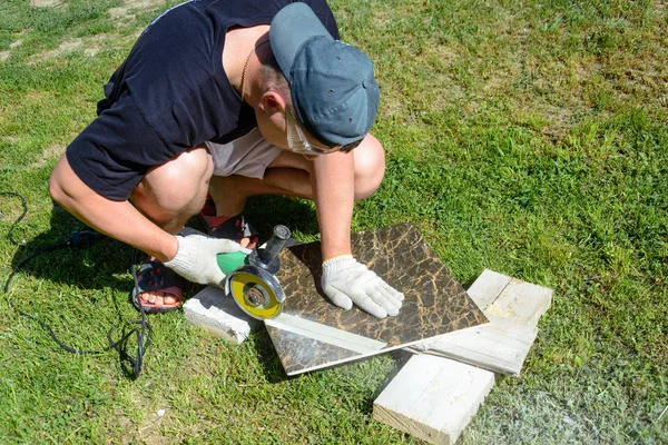 The plasterer master cuts the marble tile round the ceramic disc