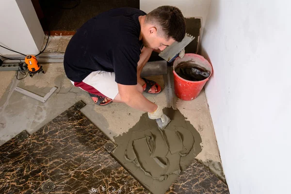 Майстер чоловік пресує шпатель клейовим розчином на цементну поверхню — стокове фото