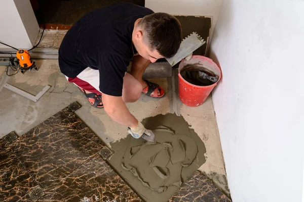 Майстер чоловік пресує шпатель клейовим розчином на цементну поверхню — стокове фото