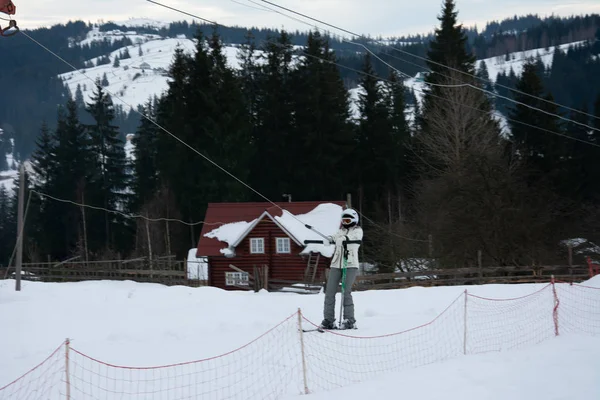 Schöne weiße Winterlandschaft mit Berglandschaften in den Karpaten mit traditionellen Häusern. schneebedeckte Berge und manuelle Lifte. Skifahrer und Snowboarder fahren bergab ins Dorf. — Stockfoto