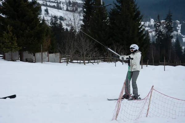 Schöne weiße Winterlandschaft mit Berglandschaften in den Karpaten mit traditionellen Häusern. schneebedeckte Berge und manuelle Lifte. Skifahrer und Snowboarder fahren bergab ins Dorf. — Stockfoto