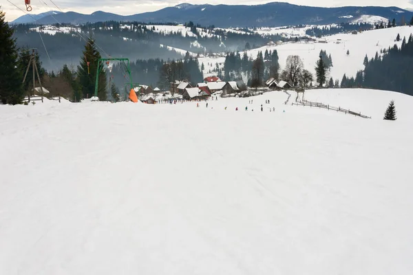 Les skieurs se reposent dans le village ukrainien des Carpates en hiver . — Photo