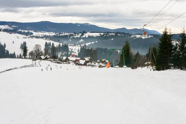 Les skieurs se reposent dans le village ukrainien des Carpates en hiver . — Photo