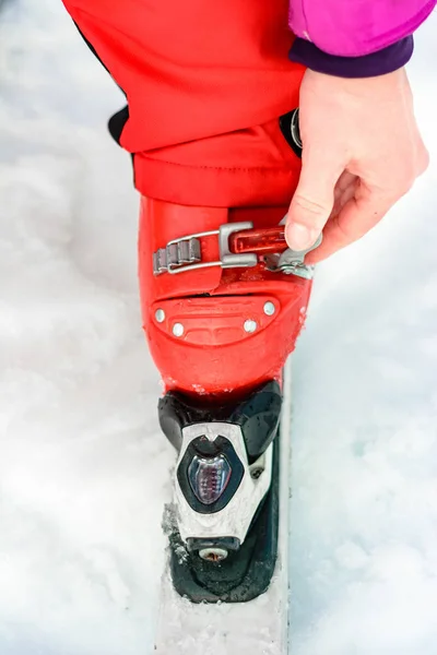 Narciarz w czerwonym stroju narciarskim i czerwonych butach narciarskich i białych nartach, zbliżenie. — Zdjęcie stockowe