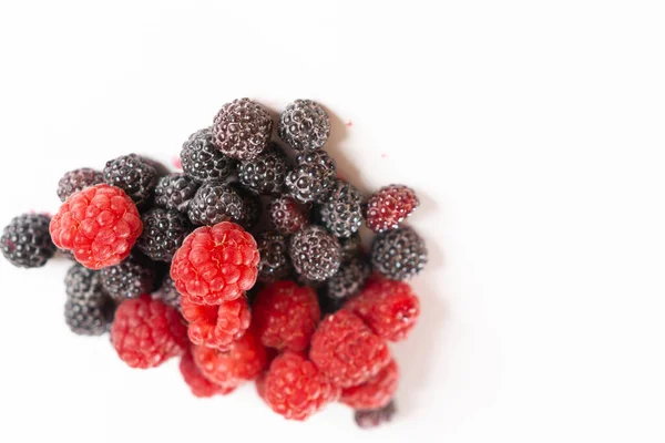 Rote und schwarze Himbeeren Nahaufnahme auf weißem Hintergrund. — Stockfoto