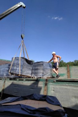 Köydeki işçiler paletleri dolandırıcılık için ön tuğlayla boşaltıyor.
