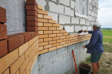 Usta, köydeki ön tuğladan bir duvar inşa ediyor..