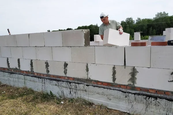 건축 현장에서 일하는 사람 이 석조 벽에 블록을 설치하고 접착제와 보조 공구를 사용 한다. — 스톡 사진