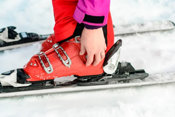 Sport zestaw nart, butów i kijów w czerwieni na kobiecej nodze zbliżenie. — Zdjęcie stockowe