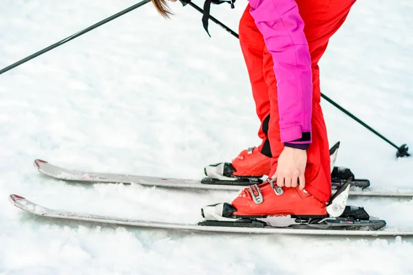 Sportset aus Skiern, Stiefeln und Stöcken in Rot am Bein der Frau aus nächster Nähe. — Stockfoto