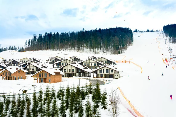 Lift und Skipiste mit Skifahrern darunter an einem sonnigen Wintertag mit blauem Himmel, Skigebiet Bukovel. — Stockfoto