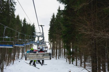 Sandalye kalkıyor ve elementler kapanıyor, kayakçılar sandalyede oturuyor..
