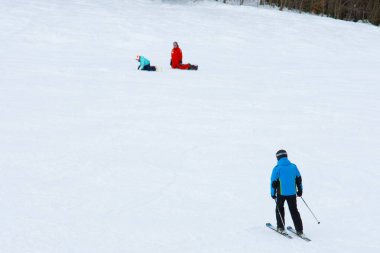 Kayakçılar Karpatlar 'ın yamaçlarından ve dağlarından inerler, arka planda resim gibi manzaralar ve kayak pistleri vardır..