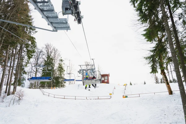 Um elevador de cadeira e seus elementos de perto, esquiadores estão sentados em cadeiras . — Fotografia de Stock