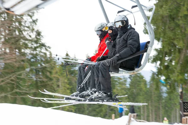 在阳光明媚的冬日里，滑雪场的椅子电梯上的人爬上了滑雪场. — 图库照片